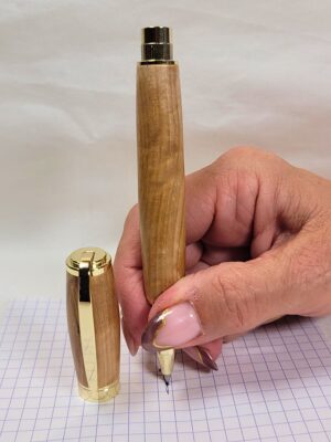 Stylo roller magnétique artisanal en bois d'alisier avec placage doré en position d'écriture