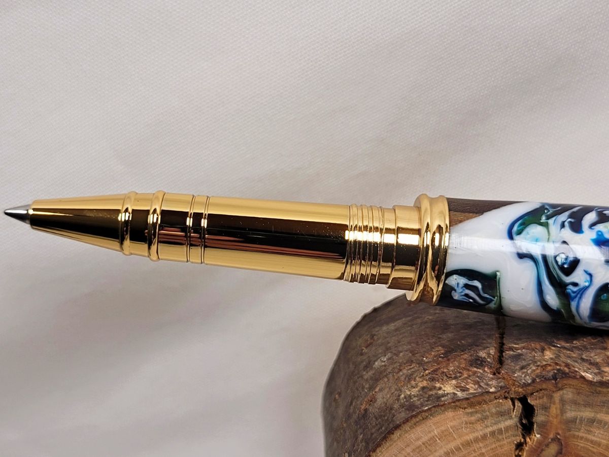 Gros plan sur la pointe et le mécanisme doré d'un stylo roller artisanal en bois et résine époxy, équipé d'une cartouche à bille céramique pour une écriture fine et fluide