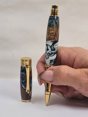 Stylo roller artisanal en bois et résine époxy tenu en main finition dorée écriture fine