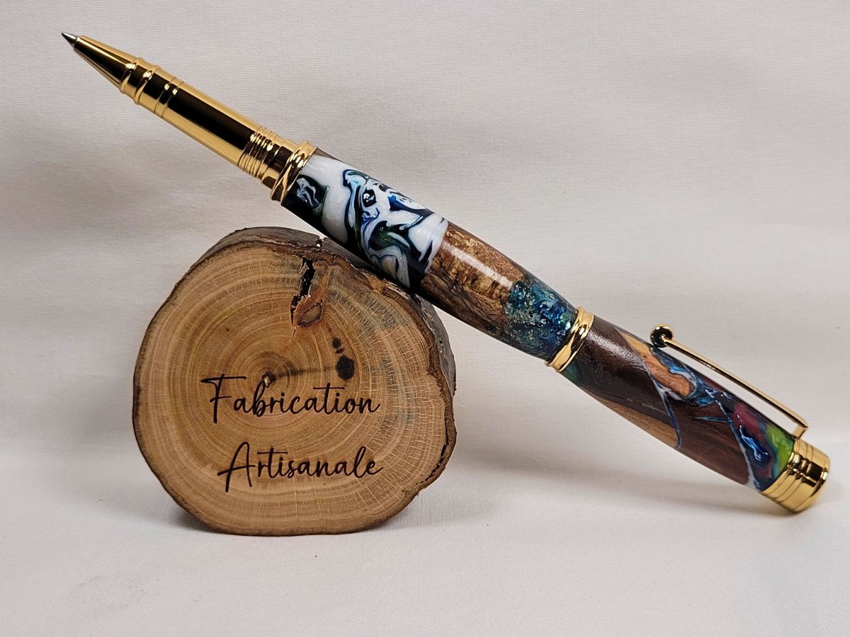 Vue complète d'un stylo roller artisanal en bois naturel et résine époxy aux nuances bleu, blanc, vert et noir, finition placage doré brillant, création artisanale française