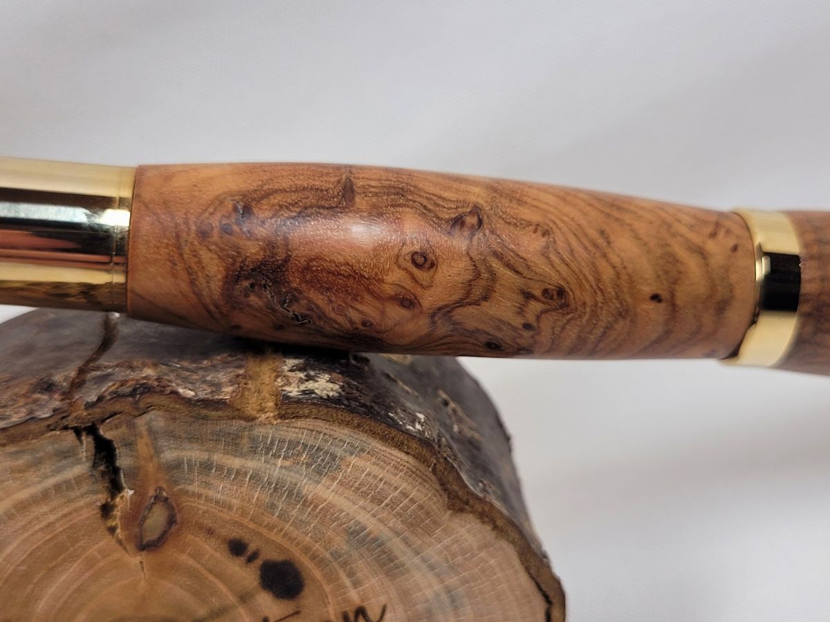 Détail des veinages exceptionnels d'un roller artisanal en bois d'olivier plaqué or, pièce unique réalisée à la main, révélant toute la beauté naturelle et les dessins uniques de cette essence méditerranéenne.