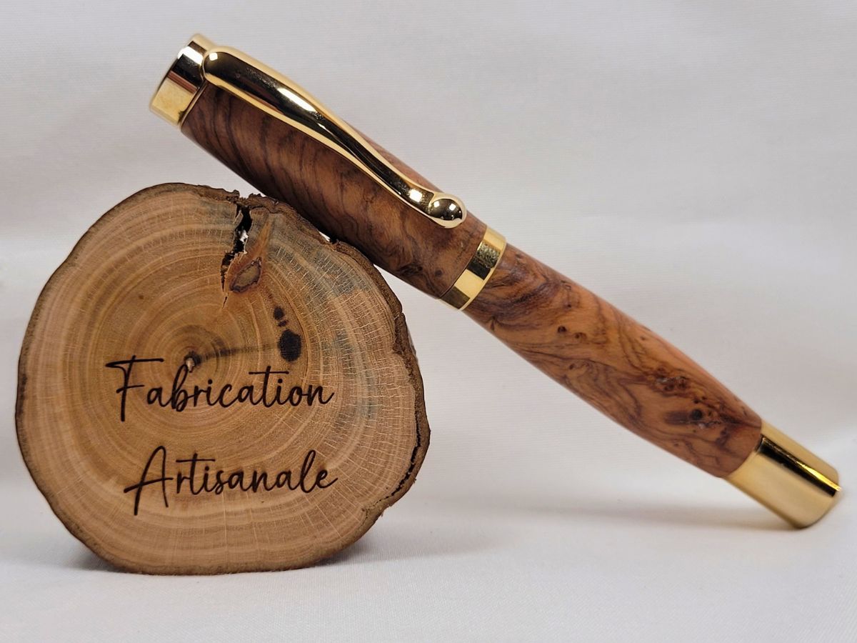 Roller de luxe artisanal en bois d'olivier avec placage or brillant, clip doré et finitions soignées, pièce unique réalisée à la main pour les amateurs de beaux instruments d'écriture.