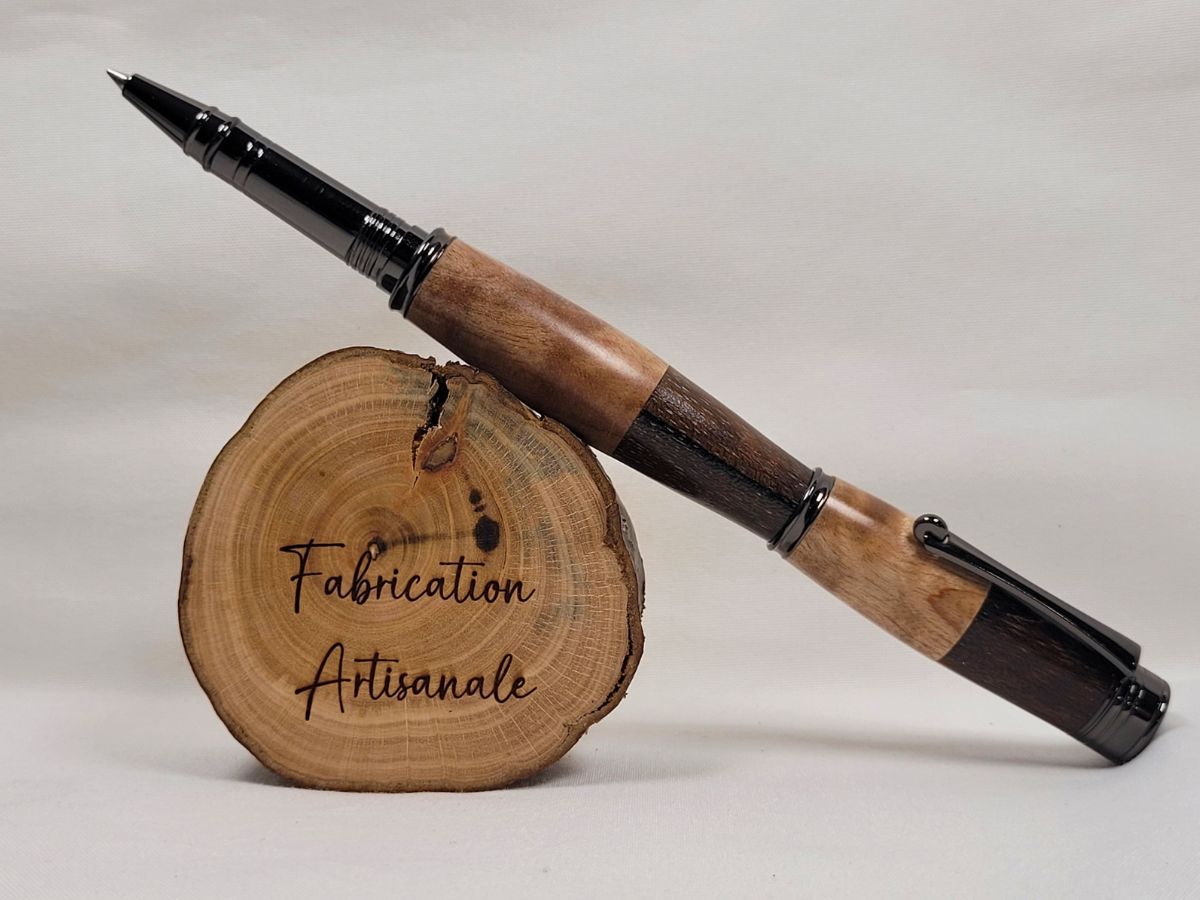 Stylo roller artisanal à capuchon vissé en bouleau ondé et palissandre, finition placage noir brillant. Le contraste entre les veines claires du bouleau et les nuances sombres du palissandre met en valeur cette création unique réalisée à la main dans un atelier français.