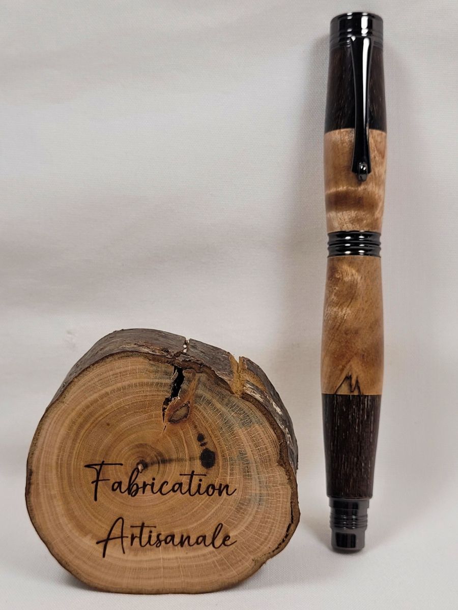 Stylo roller artisanal en bouleau ondé et palissandre avec capuchon vissé et finition placage noir. Les différentes essences assemblées révèlent un mariage harmonieux de teintes claires et foncées ainsi qu'un veinage naturel unique sur chaque exemplaire.