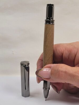 Stylo roller en noyer tenu en main avec capuchon magnétique hexagonal noir et écriture fluide