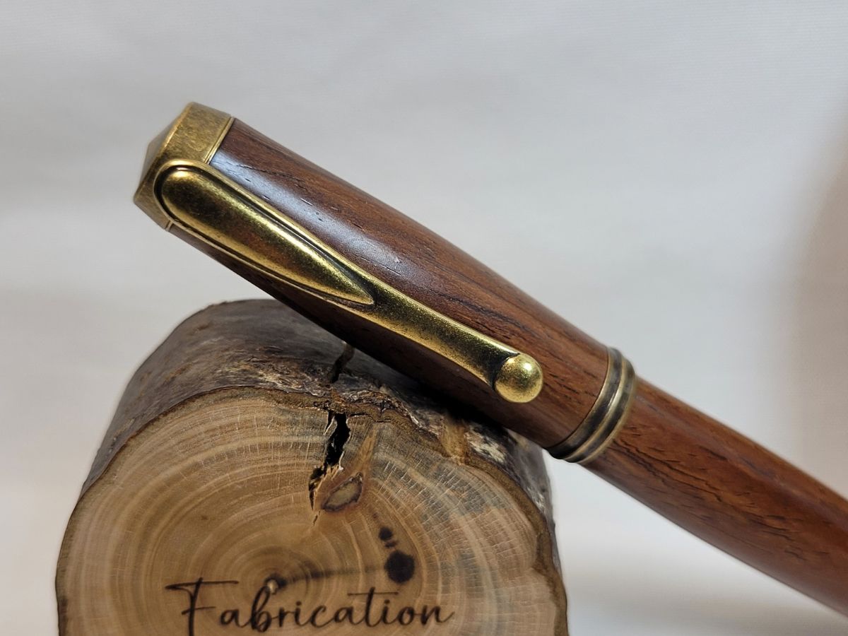 Gros plan sur l'épingle stylée bronze d'un stylo roller en padouk