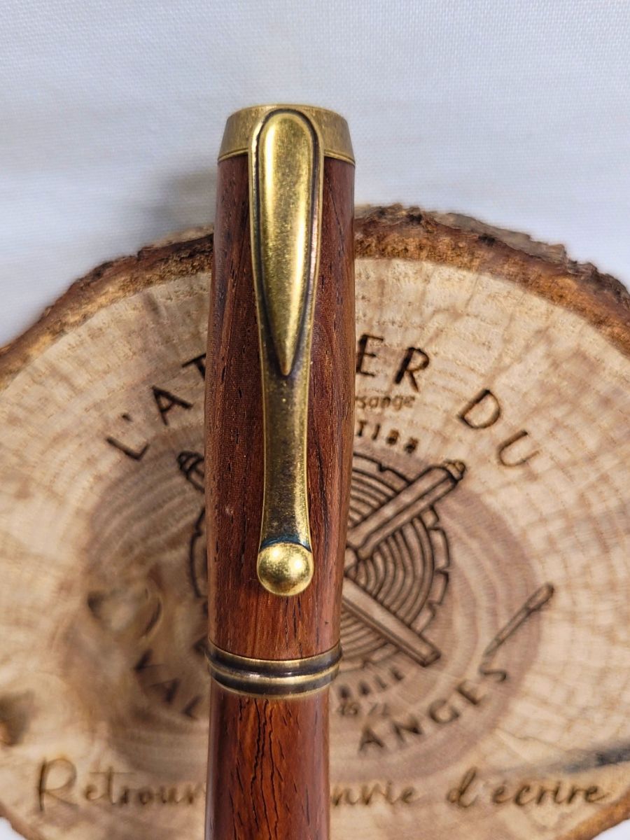 Détail du clip bronze antique sur roller artisanal en bois de padouk