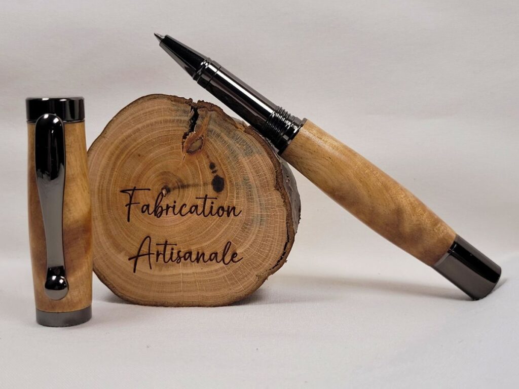 Roller artisanal en bouleau ondé ouvert avec finition noir brillant, présentant sa pointe céramique et les reflets changeants du bois naturel aux ondes marquées.