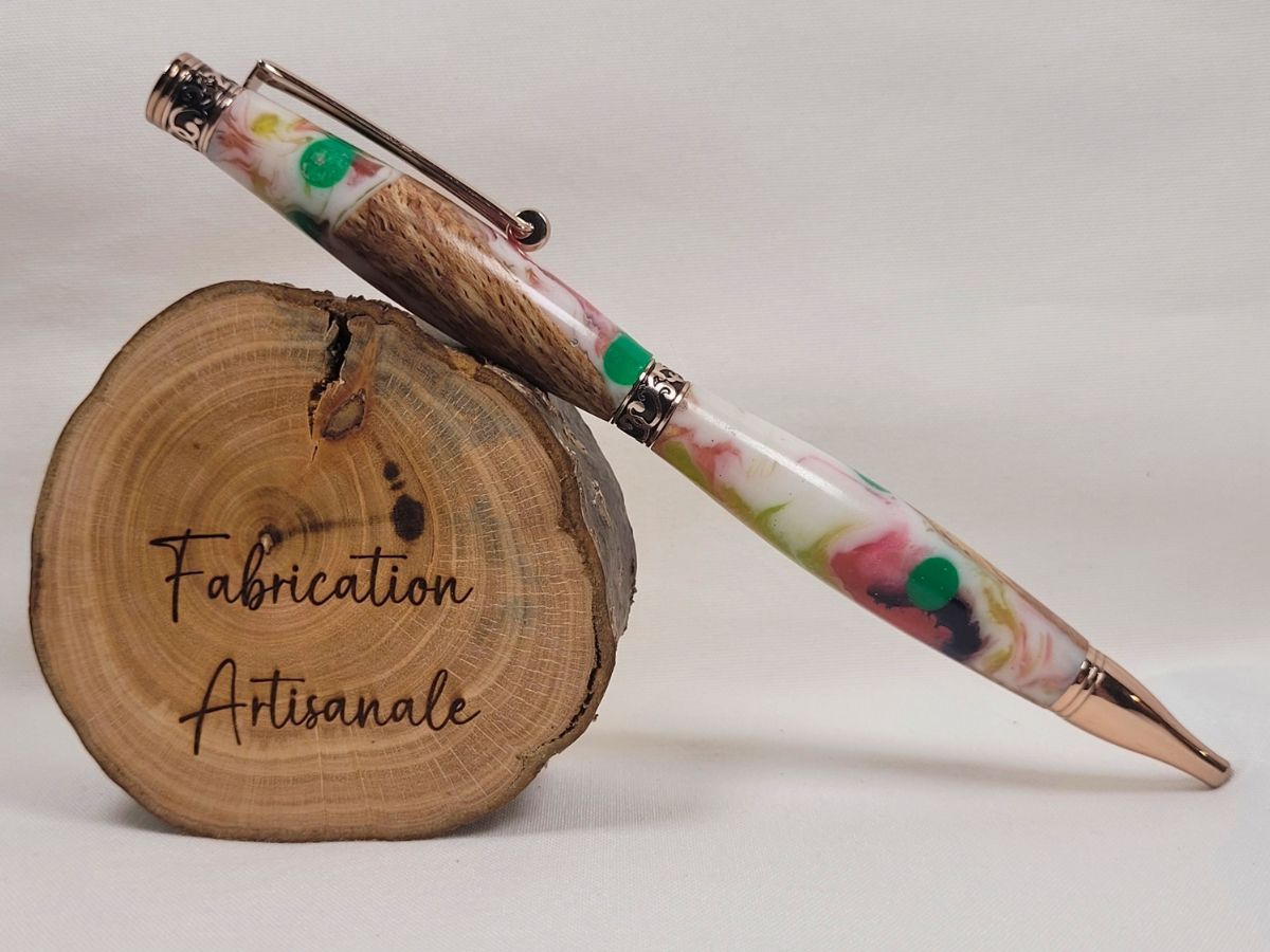 Stylo Slim Premium placage or rose posé sur rondin de bois, corps hybride hêtre et résine époxy marbrée multicolore avec pois colorés, bagues décoratives ciselées et finition brillante artisanale