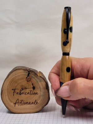 Stylo slim artisanal en bois de bouleau avec incrustations de résine colorée tenu en main pour illustrer ses dimensions, finitions noir mat, clip à épingle boule et mécanisme rotatif twist, pièce unique fabriquée dans la vallée de la Fensch