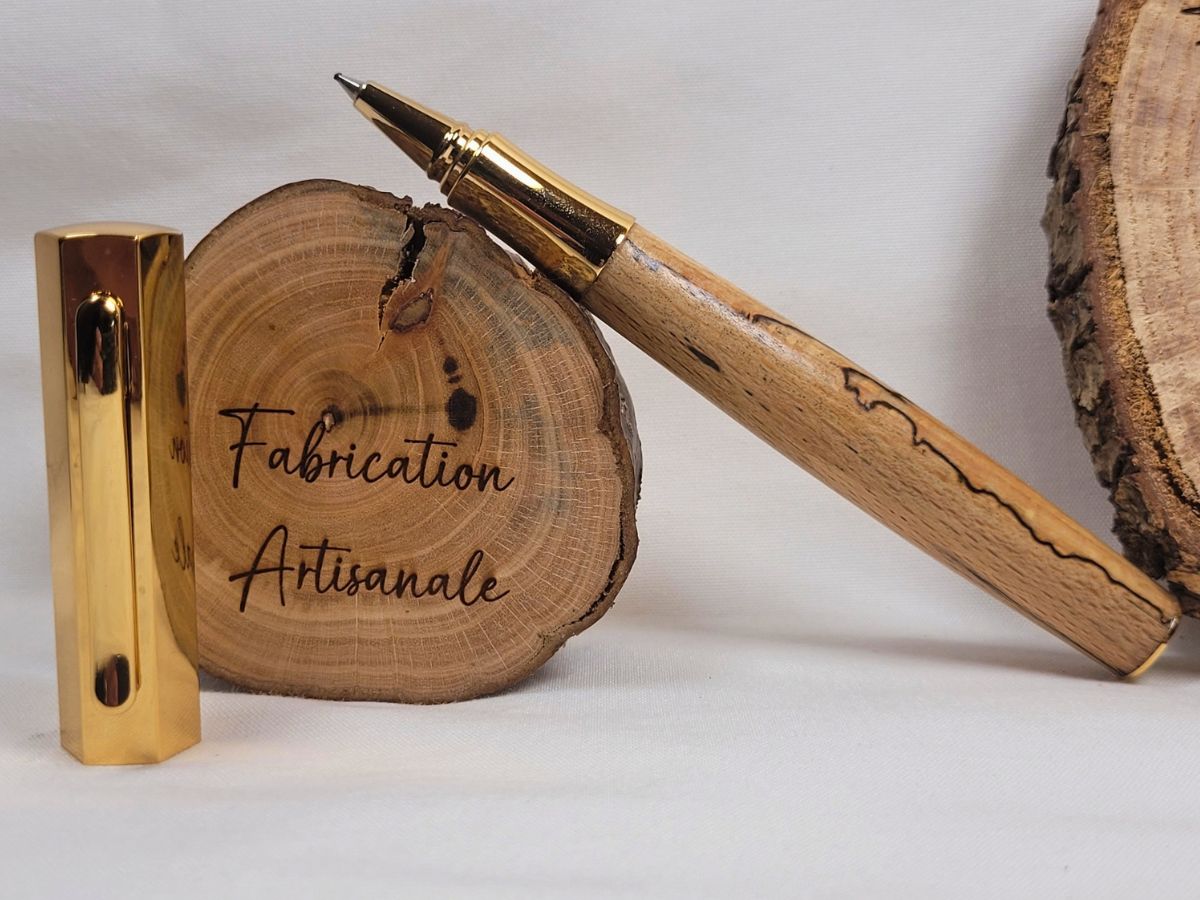 Stylo roller en hêtre échauffé avec placage doré, présenté ouvert pour mettre en valeur la pointe ergonomique et les lignes noires naturelles du bois.