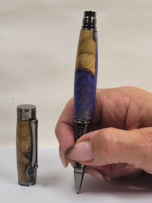 Démonstration de prise en main d'un stylo roller artisanal en hêtre et résine époxy mauve, finition noir brillant, illustrant son ergonomie et son confort d'écriture.