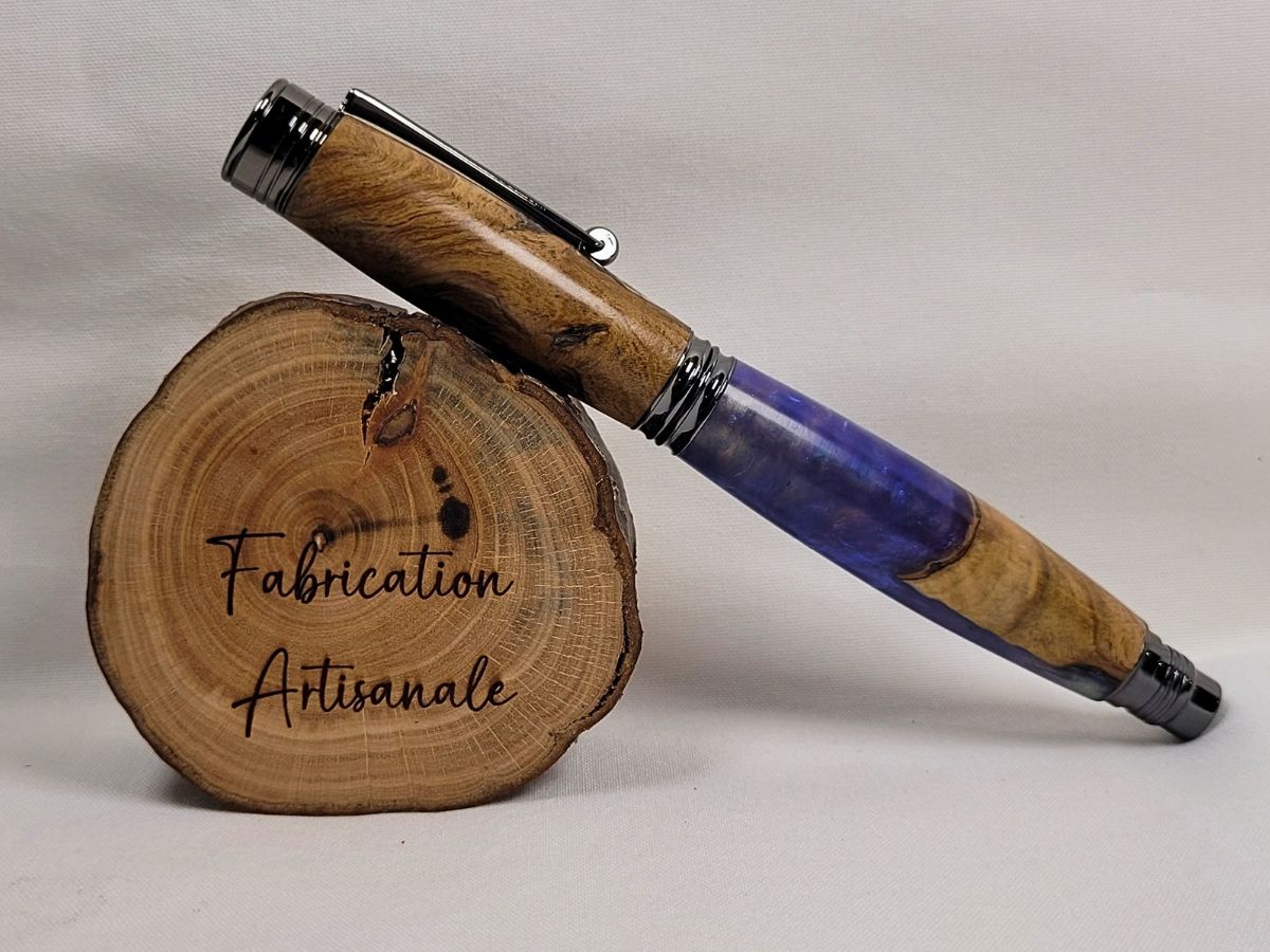 Stylo roller hybride hêtre et résine époxy mauve avec finitions noir brillant, présenté fermé afin de mettre en valeur le veinage naturel du bois et la profondeur de la résine.