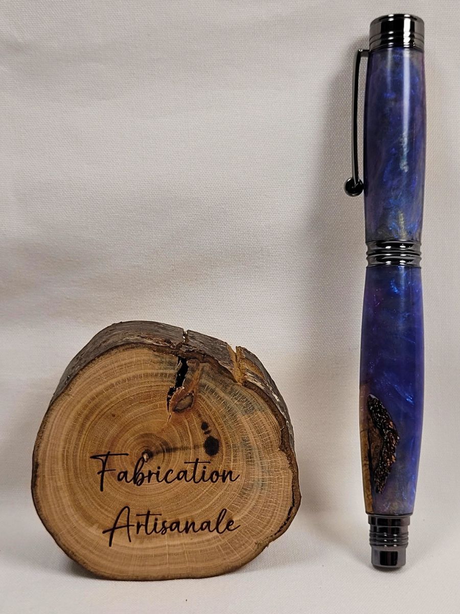 Stylo roller artisanal en hêtre et résine époxy mauve présenté fermé sur fond blanc. Une inclusion naturelle du bois apparaît dans la résine translucide, créant un motif unique. Les garnitures noir brillant soulignent l'élégance de cette création artisanale française entièrement tournée et polie à la main.